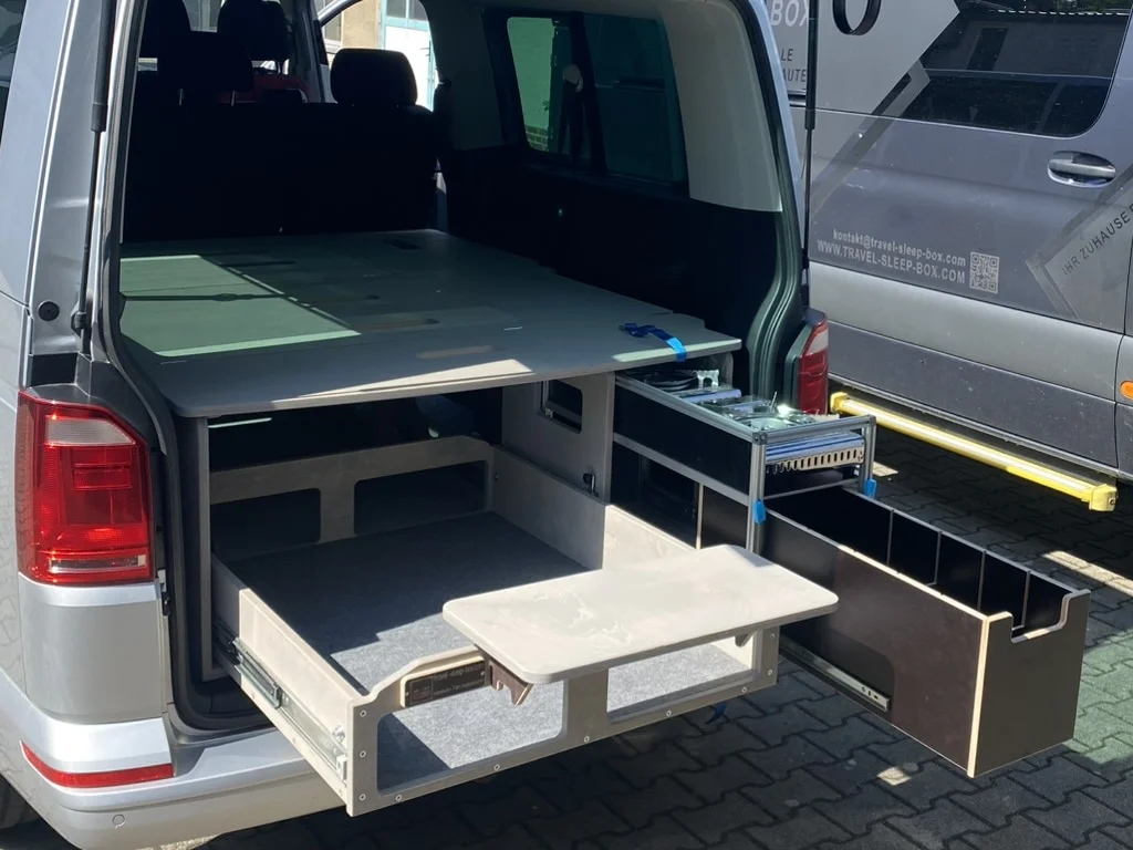 TRAVEL-SLEEP-BOX im VW T5/T6.1 Caravelle, langer Radstand, zeigt kompakte, ausziehbare Schlaf- und Staulösung.