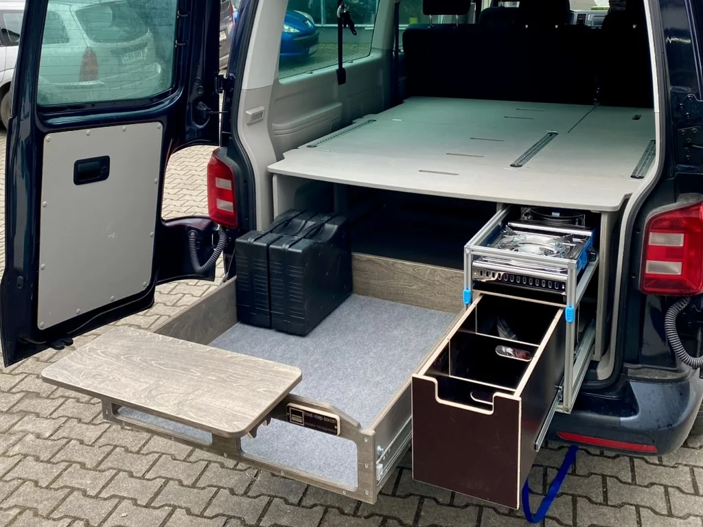 TRAVEL-SLEEP-BOX im VW T5/T6.1 Caravelle, langer Radstand, geöffneter Stauraum, leicht zugänglich und ausziehbar.